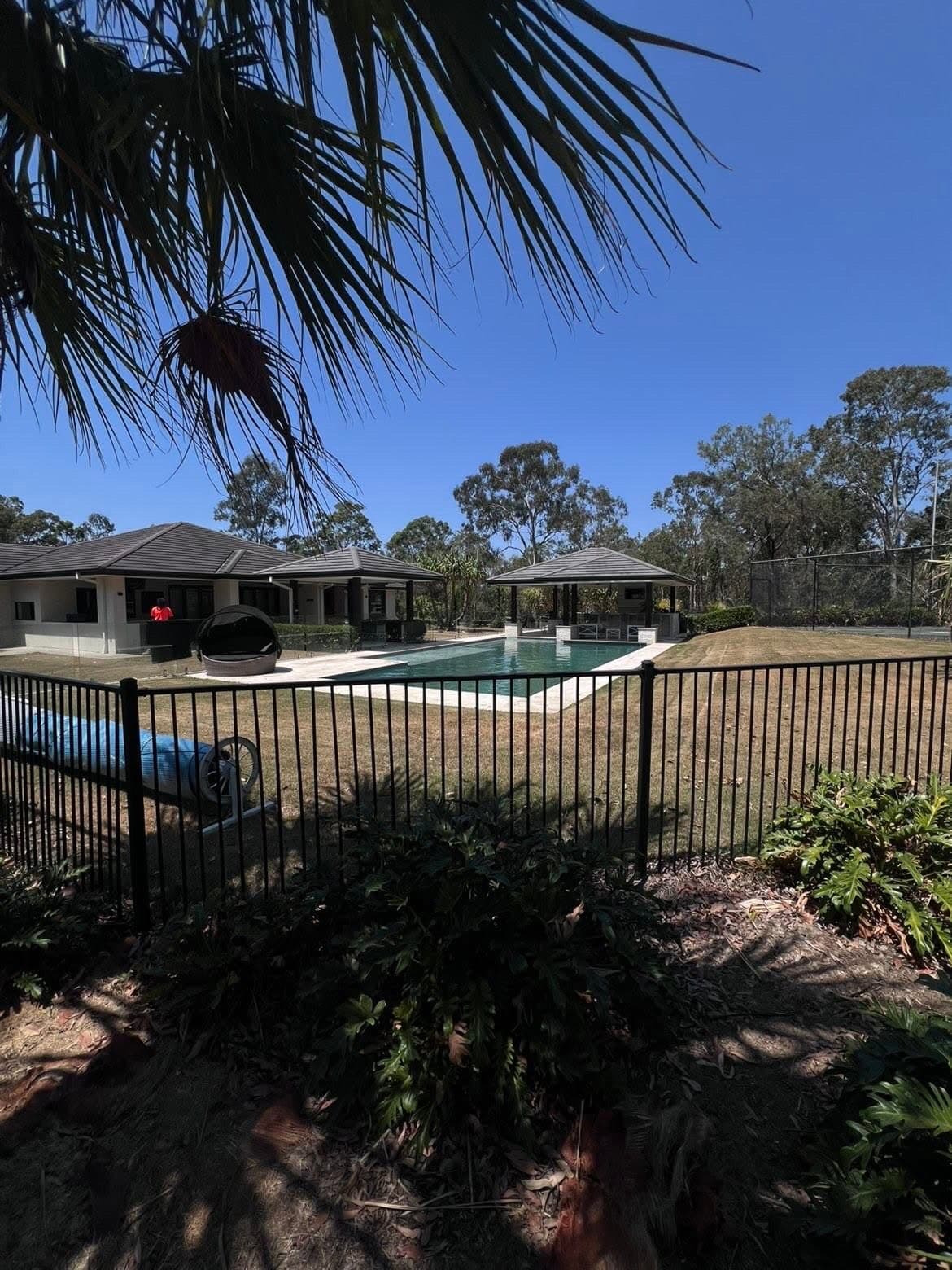 Acreage pool area bordered by maintained lawn and garden beds