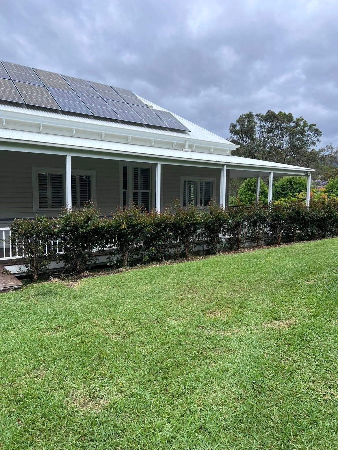 Queenslander frontage with a trimmed hedge and maintained lawn